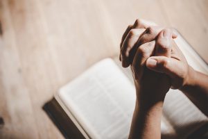 hands praying to god with the bible.